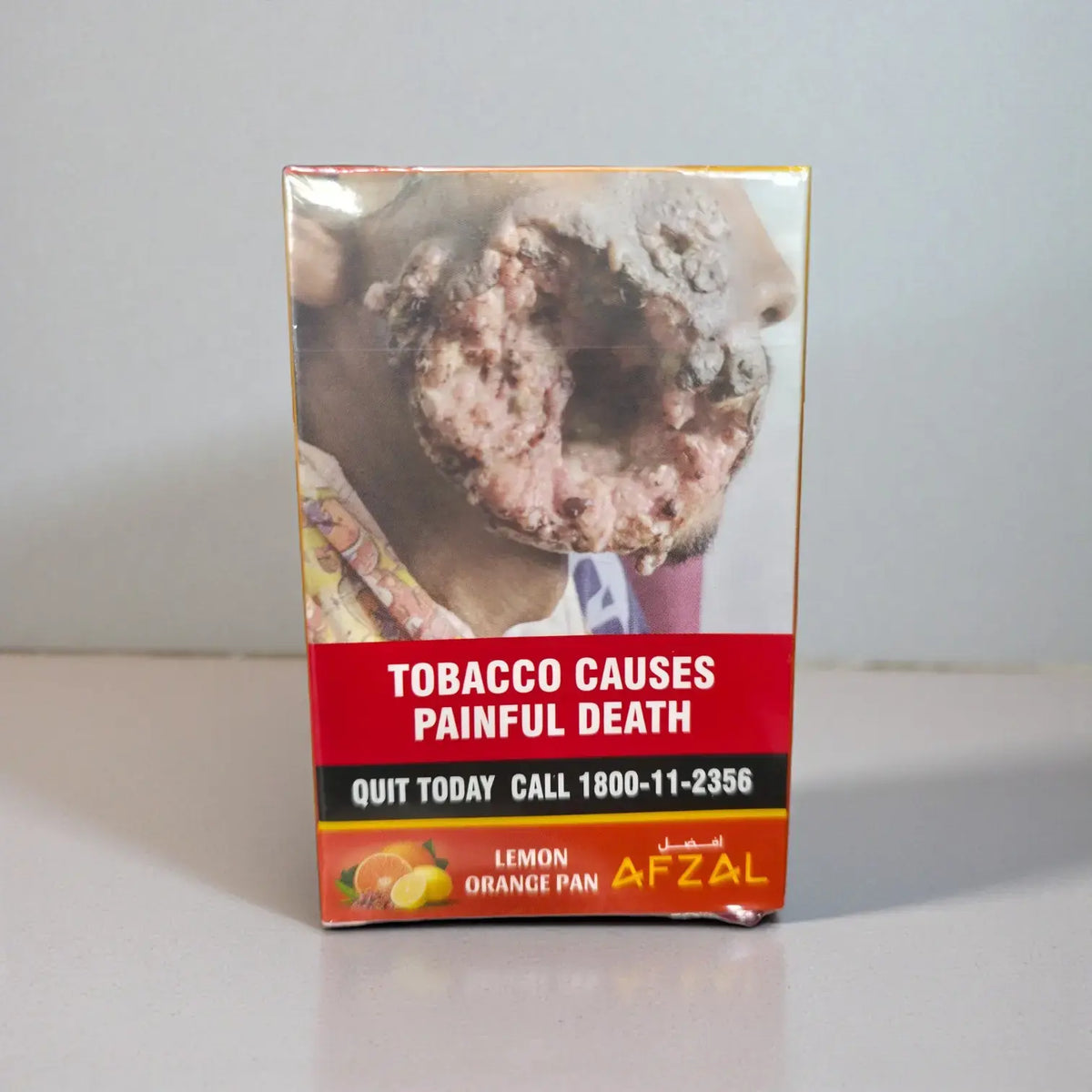 A boxed cigarette product labeled 'LEMON ORANGE PAN' with a warning panel reading 'TOBACCO CAUSES PAINFUL DEATH' and the brand name AFZAL, photographed on a plain light background.