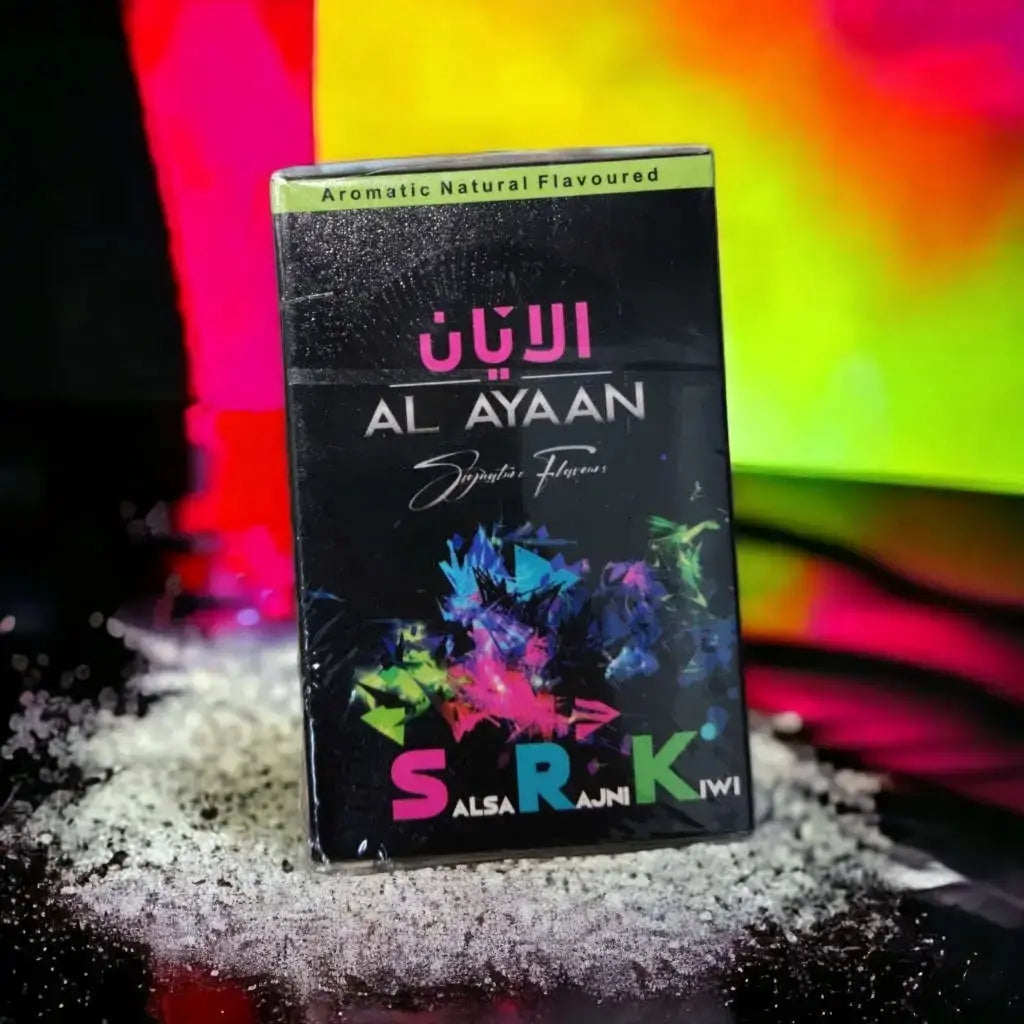 A black rectangular box of Al Ayan Syrupton Flavourers, featuring Arabic and English text, colorful abstract paint splatters, and the brand name 'S.R.